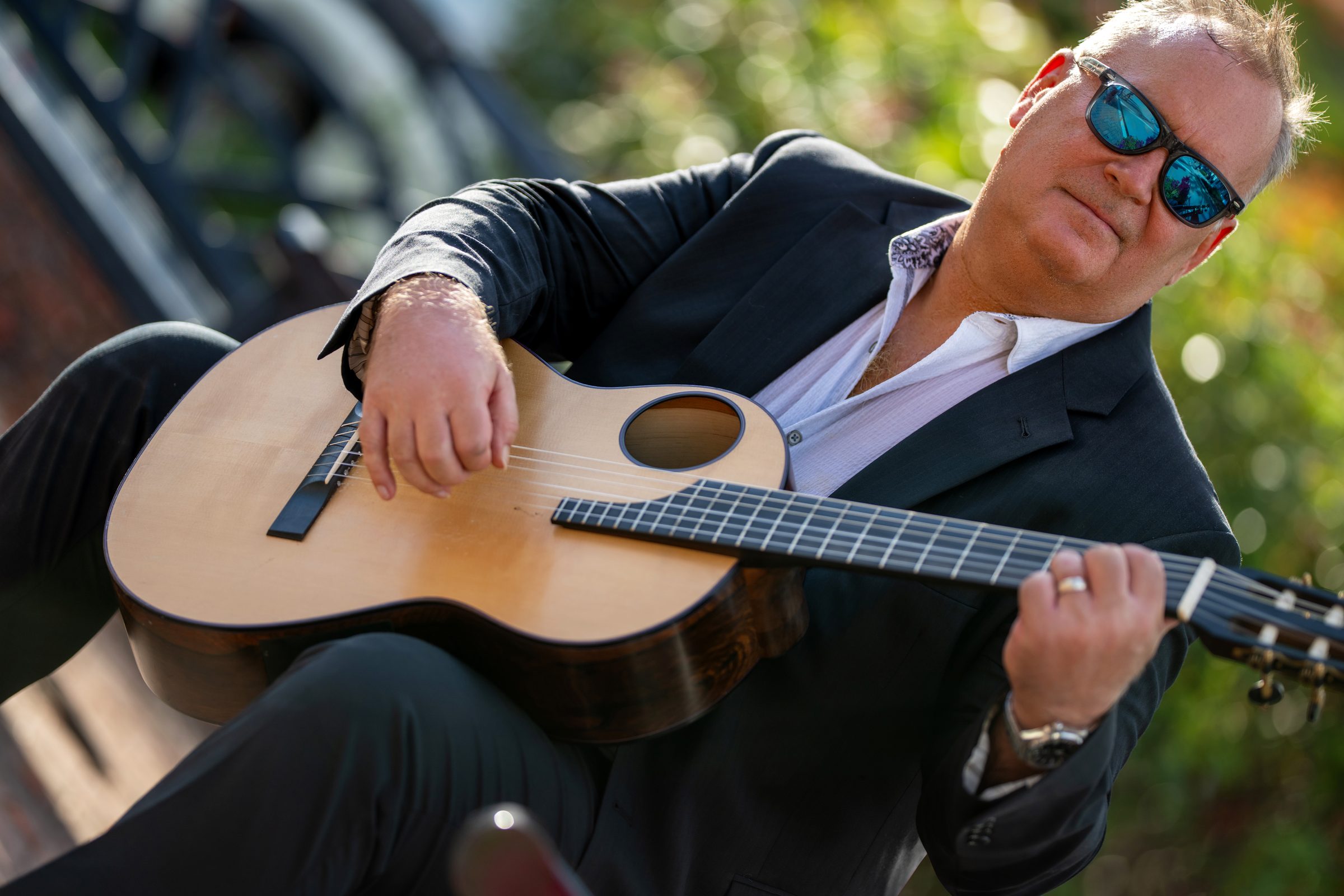 Mark Welch playing a steel-string guitar outdoors in warm afternoon light